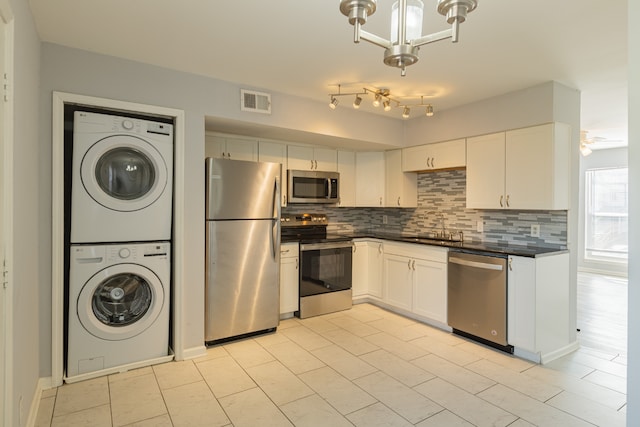 kitchen with white cabinets, sink, stacked washer and dryer, and stainless steel appliances