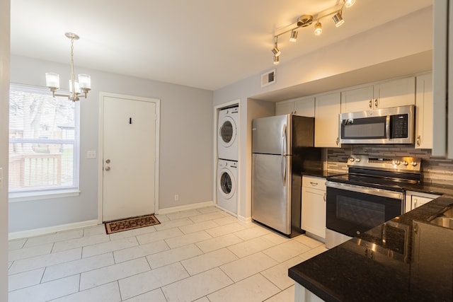 kitchen with decorative light fixtures, decorative backsplash, stacked washer / drying machine, white cabinetry, and stainless steel appliances