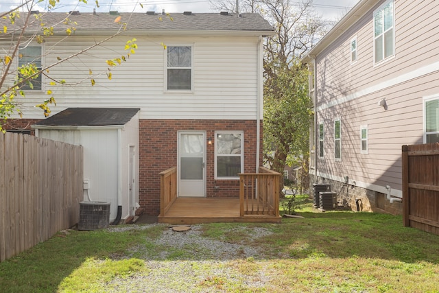 rear view of property with central air condition unit, a lawn, and a wooden deck