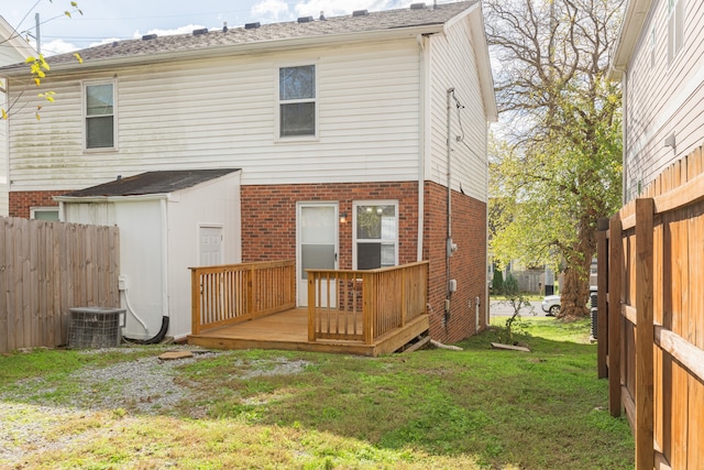 rear view of property with a lawn, a wooden deck, and central AC