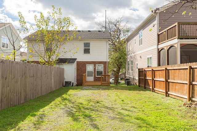 rear view of house featuring a deck, a yard, and central air condition unit