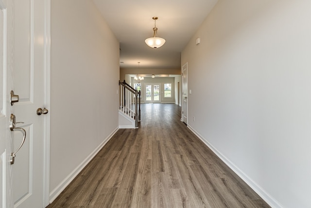 hall featuring dark wood-type flooring and an inviting chandelier