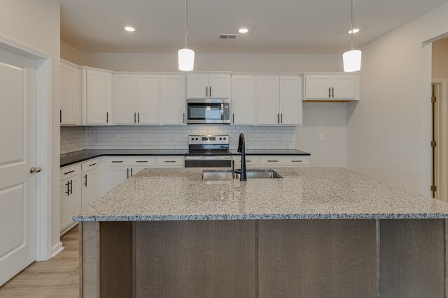 kitchen with white cabinets, dark stone countertops, stainless steel appliances, and hanging light fixtures