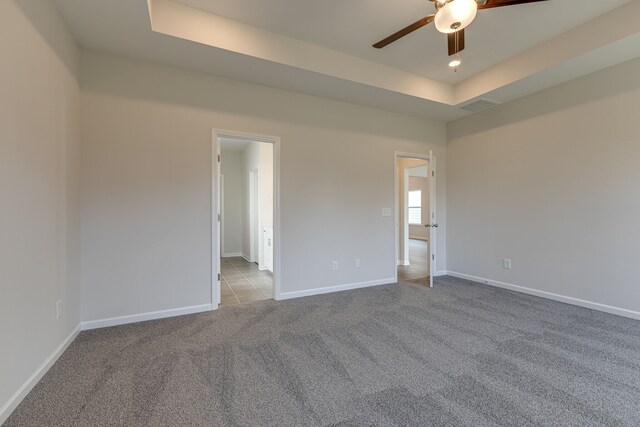 carpeted spare room featuring ceiling fan and a raised ceiling