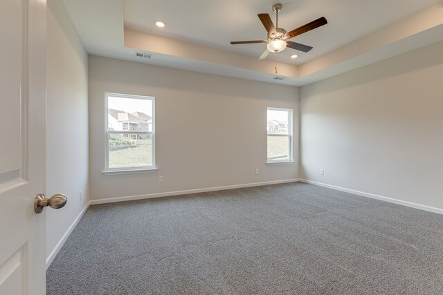 unfurnished room with a tray ceiling, ceiling fan, and carpet flooring