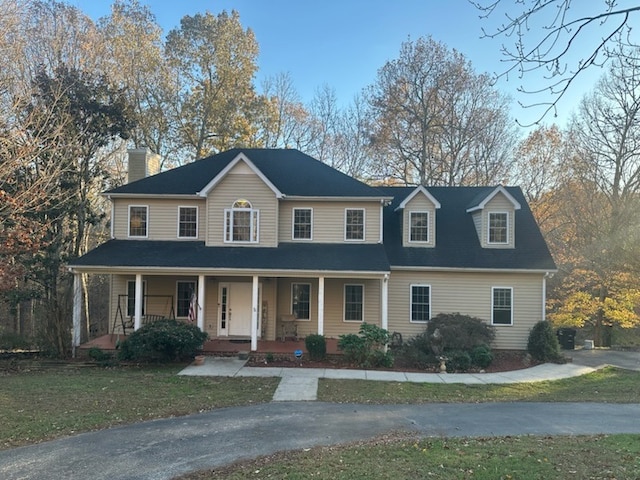 view of front of home with covered porch and a front lawn