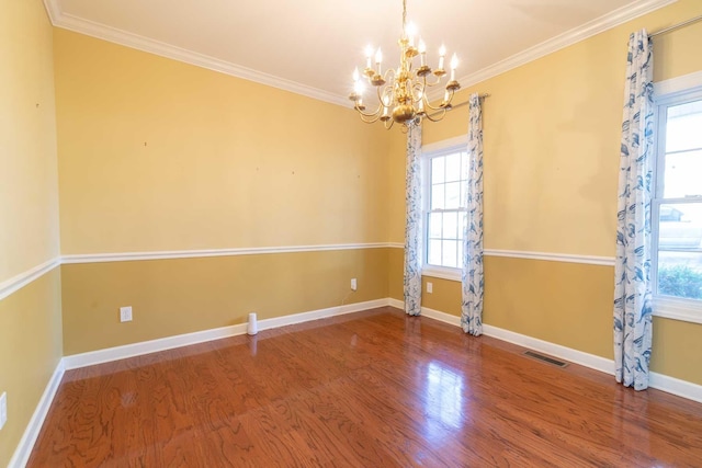 empty room featuring hardwood / wood-style floors, crown molding, and a notable chandelier