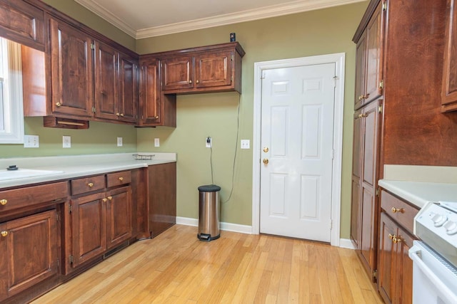 kitchen with sink, range, ornamental molding, and light hardwood / wood-style flooring