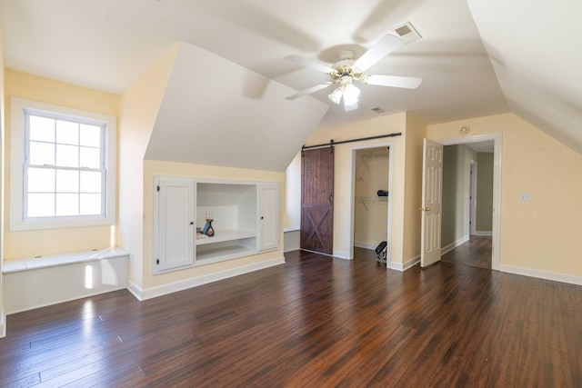 bonus room featuring ceiling fan, dark hardwood / wood-style floors, a barn door, and lofted ceiling