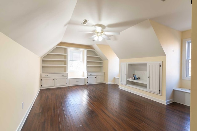 bonus room with built in shelves, ceiling fan, dark wood-type flooring, and lofted ceiling