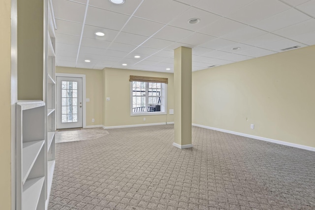 basement with a drop ceiling, a healthy amount of sunlight, and carpet