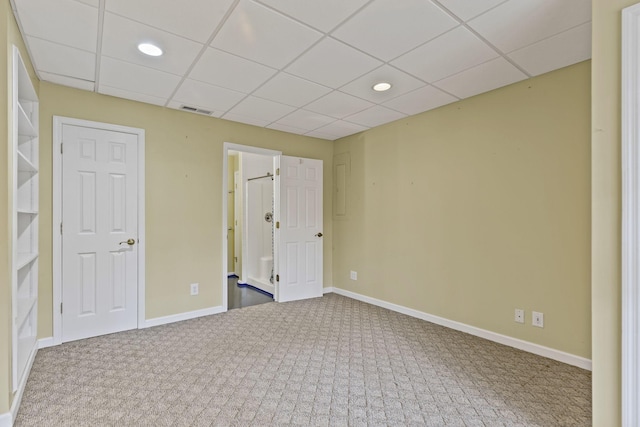 carpeted spare room with a drop ceiling