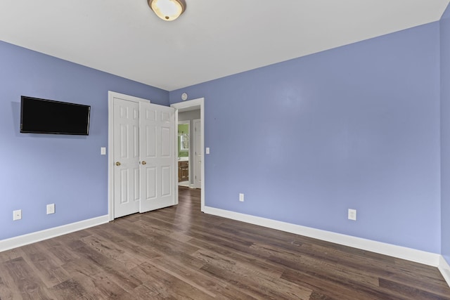 unfurnished bedroom with dark hardwood / wood-style floors and a closet