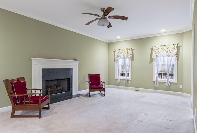 sitting room with ceiling fan, light colored carpet, a high end fireplace, and ornamental molding