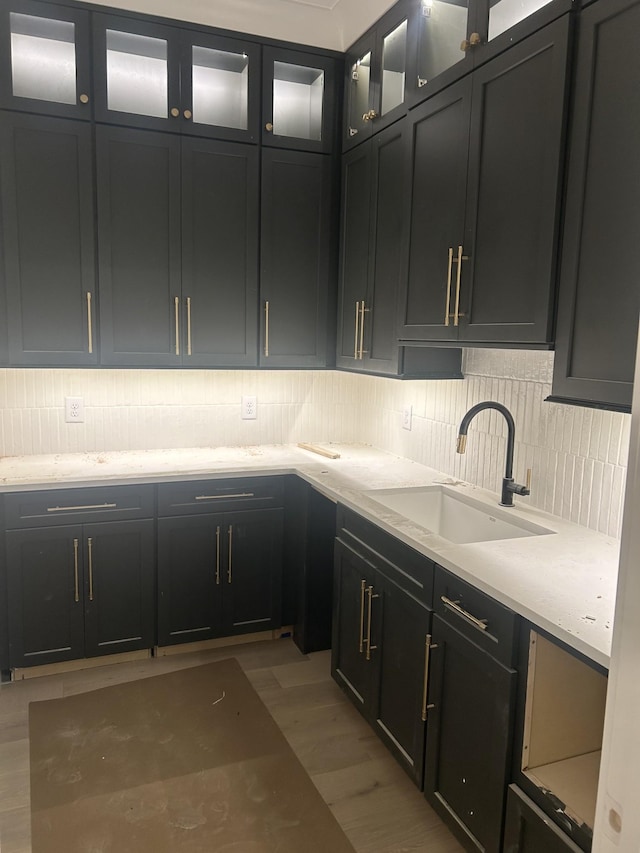 kitchen featuring light hardwood / wood-style floors, light stone countertops, sink, and backsplash