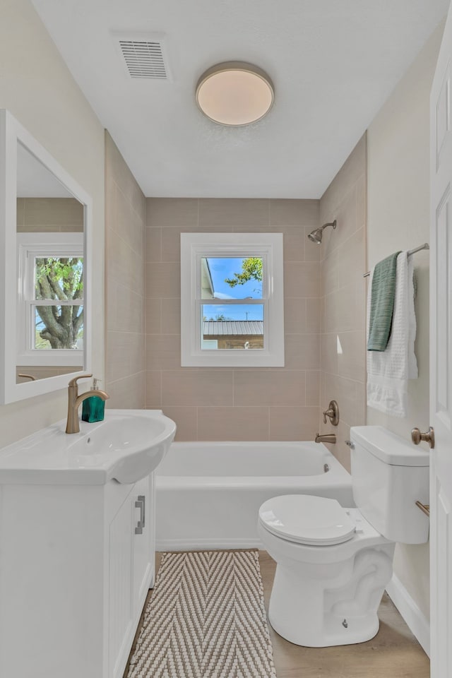 full bathroom featuring wood-type flooring, vanity, toilet, and tiled shower / bath combo