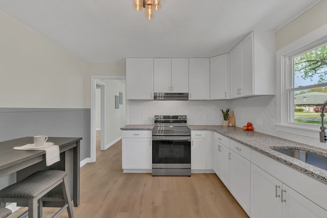 kitchen with light stone counters, white cabinets, stainless steel electric range, and light wood-type flooring