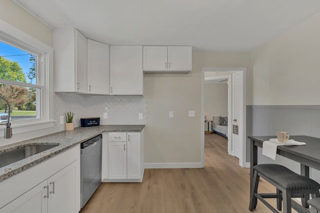 kitchen featuring dishwasher, light stone counters, white cabinetry, and light wood-type flooring