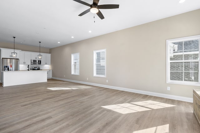 unfurnished living room featuring light wood-type flooring and ceiling fan