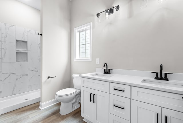 bathroom featuring tiled shower, wood-type flooring, vanity, and toilet