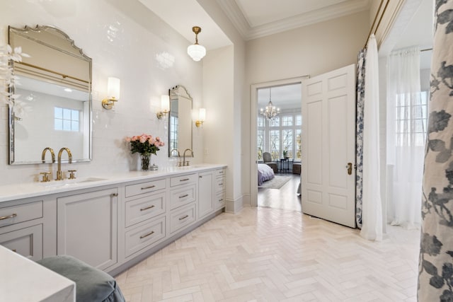 bathroom with a high ceiling, an inviting chandelier, parquet flooring, vanity, and ornamental molding