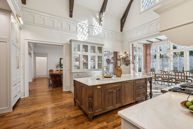 kitchen with beam ceiling, sink, hanging light fixtures, dark wood-type flooring, and high vaulted ceiling