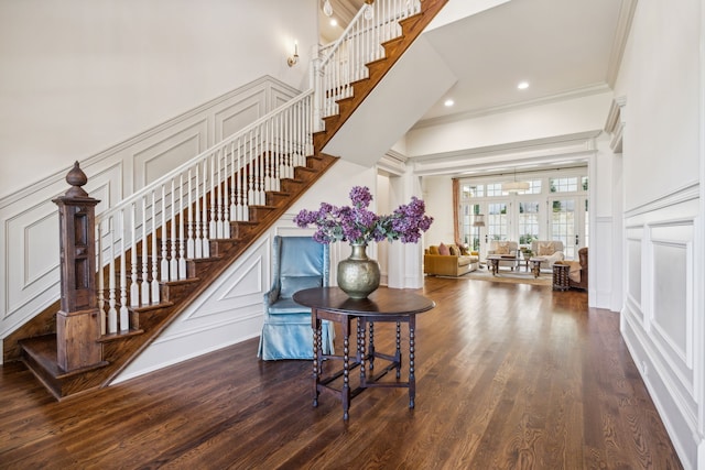 stairway with crown molding, french doors, a high ceiling, and hardwood / wood-style flooring