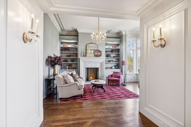 living area with a premium fireplace, dark hardwood / wood-style flooring, an inviting chandelier, and ornamental molding