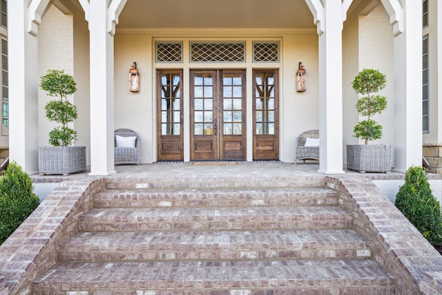 view of exterior entry with covered porch and french doors