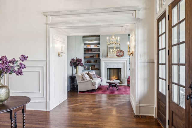 living area featuring plenty of natural light, dark hardwood / wood-style flooring, a high end fireplace, and built in shelves