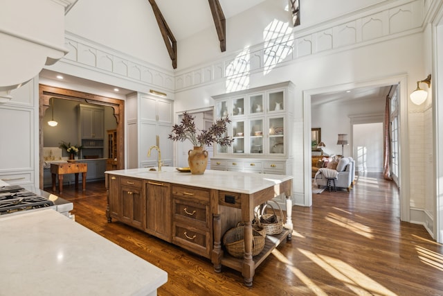 kitchen featuring dark hardwood / wood-style flooring, sink, a center island with sink, high vaulted ceiling, and beamed ceiling