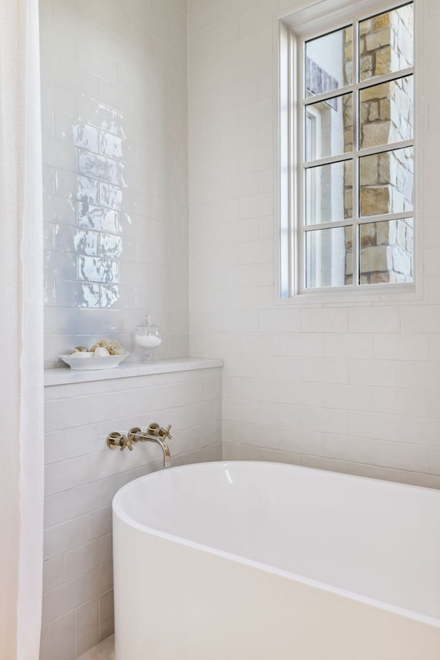 bathroom with tile walls and a tub