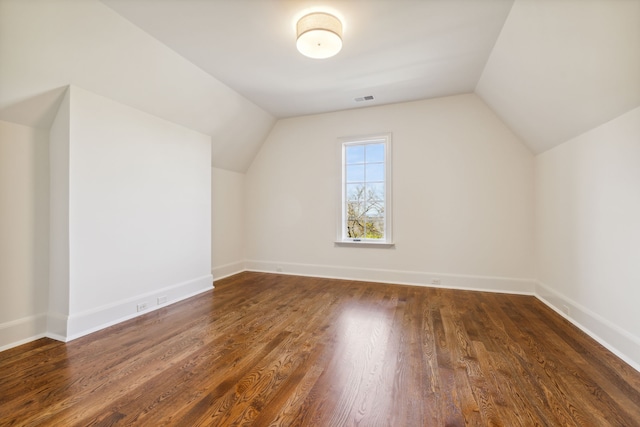 additional living space featuring dark wood-type flooring and vaulted ceiling