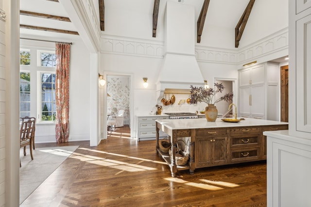 interior space with dark hardwood / wood-style flooring, beamed ceiling, high vaulted ceiling, stainless steel stove, and custom range hood