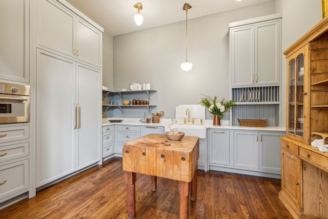 kitchen featuring sink, hanging light fixtures, dark wood-type flooring, and stainless steel oven