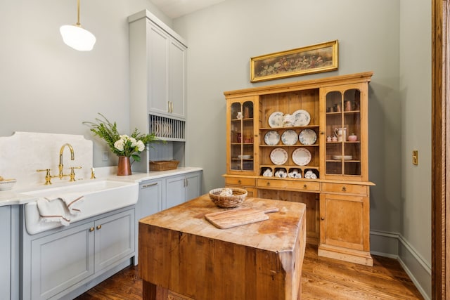 bar featuring decorative light fixtures, gray cabinets, dark hardwood / wood-style flooring, and sink