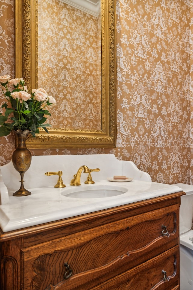 bathroom with toilet, vanity, and ornamental molding