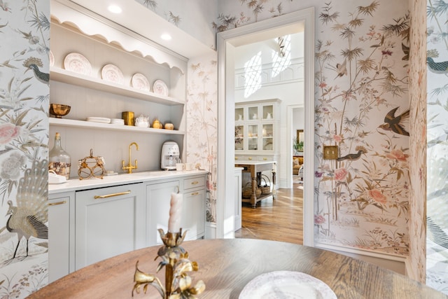 bar featuring light hardwood / wood-style floors, white cabinetry, and sink