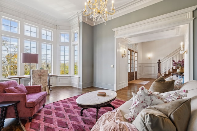 living room featuring hardwood / wood-style flooring, crown molding, a high ceiling, and a chandelier