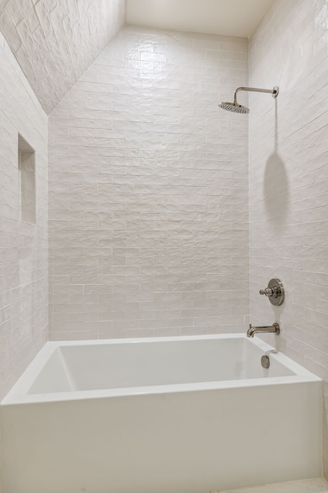 bathroom with tiled shower / bath and lofted ceiling