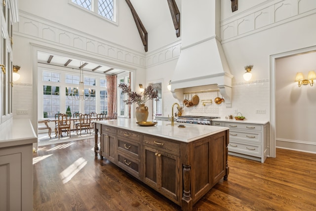 kitchen featuring custom range hood, beam ceiling, a center island with sink, high vaulted ceiling, and dark hardwood / wood-style floors