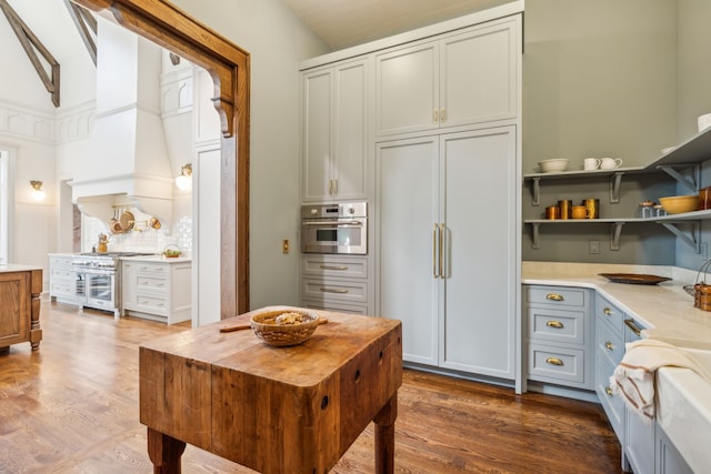 kitchen with lofted ceiling, high quality appliances, wood-type flooring, and custom range hood