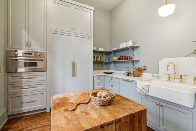 kitchen with sink, paneled fridge, dark hardwood / wood-style flooring, oven, and decorative light fixtures