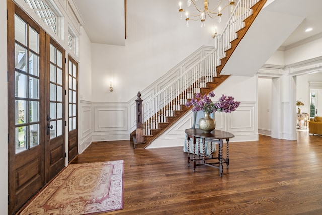 entryway with a wealth of natural light, dark wood-type flooring, a high ceiling, and french doors