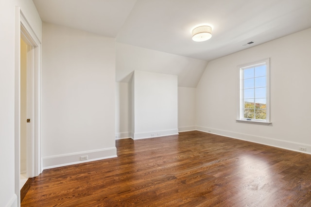 additional living space with dark wood-type flooring and vaulted ceiling