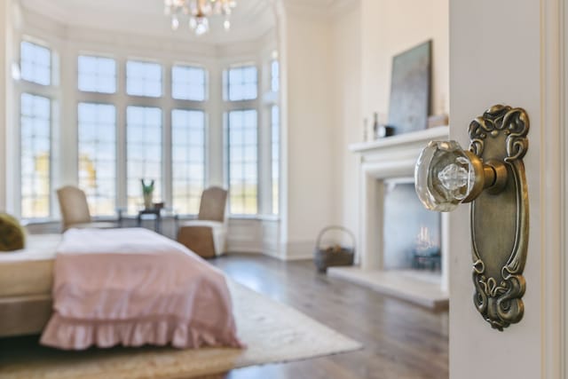 bedroom with hardwood / wood-style floors, an inviting chandelier, and crown molding