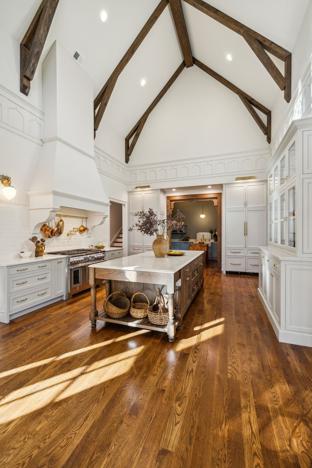 interior space with dark hardwood / wood-style flooring, custom exhaust hood, a large island, high vaulted ceiling, and a breakfast bar area