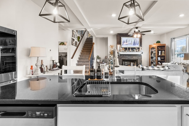 kitchen with ceiling fan, a large fireplace, dishwasher, sink, and pendant lighting