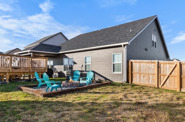 back of house with a lawn, a deck, and an outdoor fire pit