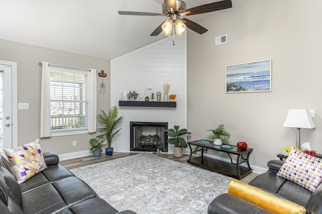 living room with ceiling fan, a large fireplace, hardwood / wood-style floors, and lofted ceiling